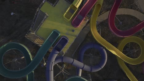 Ascending-top-down-of-abandoned-water-park-with-old-colorful-chutes