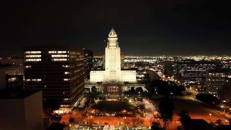 Los-Angeles,-California-at-night-with-City-Hall-illuminated---rising-aerial-reveal