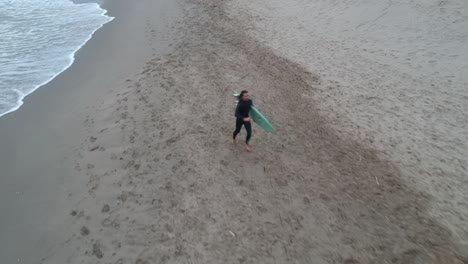 Luftaufnahmen-Eines-Strandes-Mit-Einem-Surfer,-Der-über-Den-Strand-Läuft