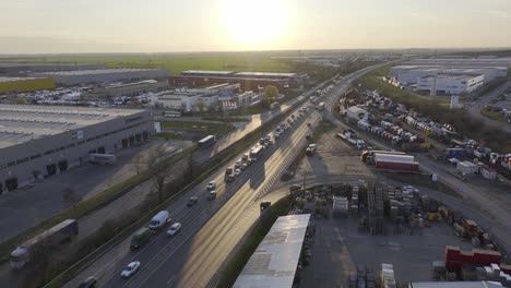 Aerial-view-of-traffic-on-highway-in-Bucharest-during-golden-sunset-at-horizon