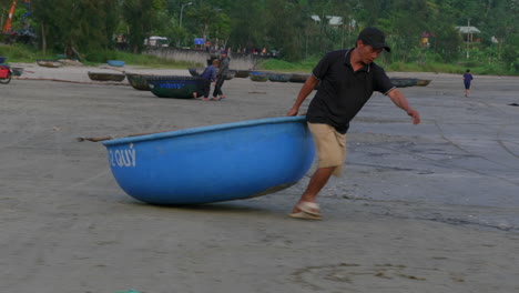 Toma-De-Seguimiento-De-Pescadores-Arrastrando-Un-Pequeño-Bote-Tradicional-Al-Agua-En-Da-Nang