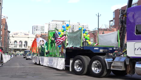 Semi-Camión-Púrpura-Tirando-De-Un-Desfile-De-Carrozas-Con-Gente-Saludando-A-La-Multitud-En-Un-Desfile-Del-Día-De-San-Patricio