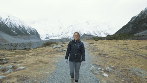 A-front-on-following-shot-of-a-woman-walking-between-snow-capped-mountains-on-a-cold-winters-morning-in-New-Zealand