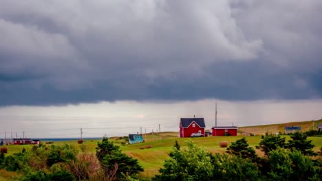 Heavy-grey-clouds-streak-across-the-sky-over-a-red-house-against-grassy-green-hills-of-the-Magdalen-Islands