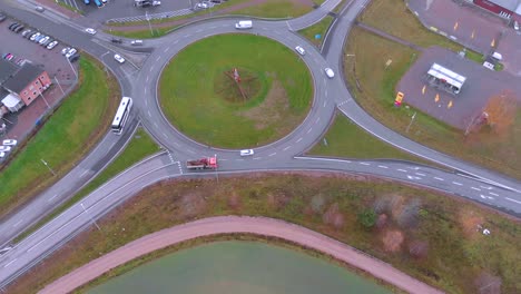 Rotating-drone-footage-of-a-roundabout-with-with-cars-driving-in-and-out-of-it,-on-a-cloudy-day-in-October