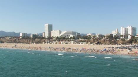 Eine-Schöne-Küstenaufnahme-Des-Berühmten-Strandes-Von-Santa-Monica-Mit-Vielen-Strandbesuchern,-Die-Den-Sommer-Genießen