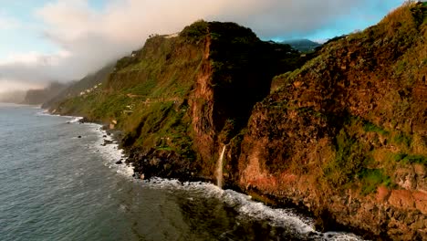 Aerial-still-of-golden-hour-coastal-waterfall-going-into-ocean,-Madiera,-Portugal