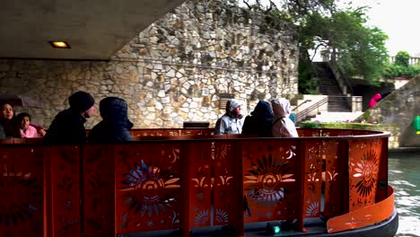 The-Riverboats-on-the-San-Antonio-Riverwalk-constantly-route-through-downtown,-who's-colorful-lights-seem-to-dance-on-the-surface