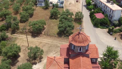 Reverse-reveal-of-small-Greek-church-to-reveal-olive-tree-plantations-and-mountains-on-Thassos-island,-Greece