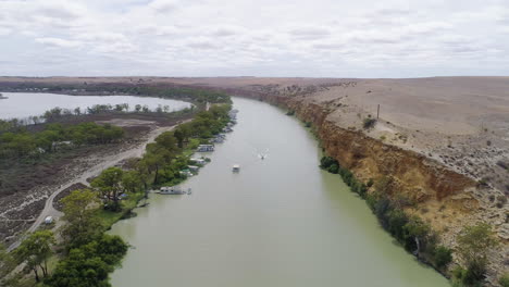 Aerial-parallax-over-the-stunning-River-Murray-in-South-Australia,-with-boats-cruising-along-the-water-below-limestone-cliffs