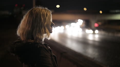 A-girl-stands-by-a-highway-at-night