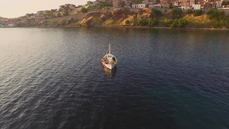 Aerial:-A-fishing-boat-in-the-bay-in-front-of-Molyvos,-Greece