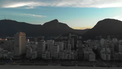 Seitlicher-Luftschwenk-über-Den-Strand-Von-Ipanema-In-Rio-De-Janeiro-Mit-Dem-Corcovado-Berg-Im-Hintergrund-Vor-Einem-Blauen-Himmel-Im-Ersten-Licht