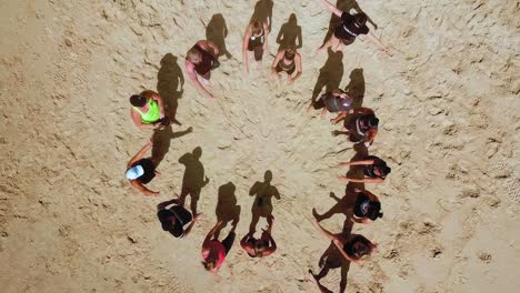Aerial-top-down-view-of-a-team-of-people-making-hand-circle-and-cheering-on-the-beach