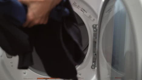Nahaufnahme-Eines-Mannes-In-Zeitlupe,-Der-Wäsche-Aus-Der-Daneben-Stehenden-Waschmaschine-In-Einen-Trockner-Lädt