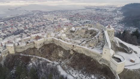 Wide-orbit-around-Rasnov-Citadel-in-Romania,-during-winter-time