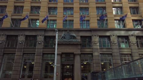 Historic-building-of-the-Commonwealth-Bank-of-Australia-with-Australian-Flags-at-Martin-Place,-Sydney,-Australia