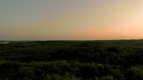 Luftaufnahmen-über-Wald-Bei-Sonnenuntergang,-Schöner-Himmel-Am-Horizont-Und-Grüne-Baumkronen-Darunter,-Naturlandschaft-In-Der-Stadt,-In-Der-Nähe-Von-Wohngebäuden