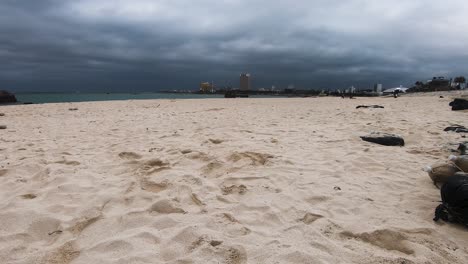 Low-angle-time-lapse-of-sand-on-Araha-Beach,-Chatan,-Okinawa,-Japan-on-a-cloudy-day