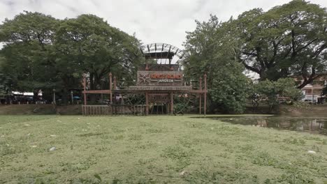 Wide-Shot-of-Water-Wheel-in-Algae-Filled-River