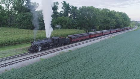 Vista-Aérea-De-Un-Tren-De-Pasajeros-De-Vapor-Esperando-En-Una-Estación-En-El-Campo-Amish-En-Un-Día-De-Verano