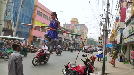 Poor-little-orphan-Indian-girl-balancing-long-stick-and-standing-on-rope-as-street-performer-and-salutes,-Slow-motion