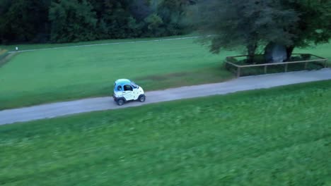Filmische-Seitliche-Drohnenaufnahme-Aus-Der-Luft,-Die-Einem-Leichten-Elektrofahrzeug-Von-Enuu-In-Der-Schweiz-Folgt