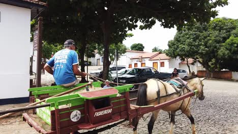 A-video-of-a-man-driving-a-horse-drawn-cart-through-the-streets-of-Pirenopolis,-Brazil