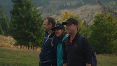 Three-friends-pose-for-the-camera,-trees-and-mountains-in-the-background