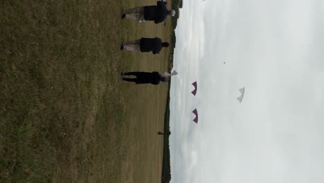 Group-of-four-adults-flying-synchronised-stunt-kites-at-the-park,-Fort-Casy,-Washington,-Vertical