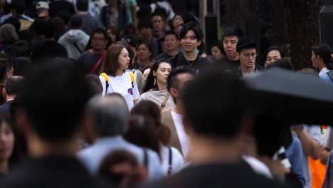 Static-shot-of-a-woman-walking-in-middle-of-a-large-crowd,-on-the-streets-of-Harajuku,-in-Tokyo,-Japan