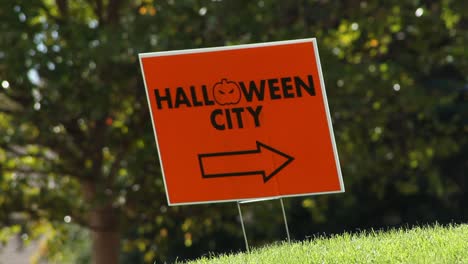 Halloween-Stadtschild,-Das-Im-Wind-Weht,-Autos-Im-Hintergrund