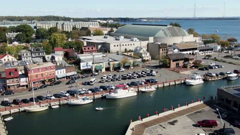 Descending-aerial-above-Ego-Alley-in-Annapolis,-boats-in-Harbor-beside-US-Naval-Academy