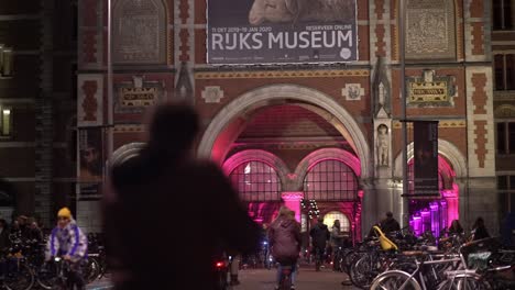 Cyclists-at-facade-of-Amsterdam-Rijksmuseum-tunnel-at-museum-night-with-riding-bicycles-on-the-street