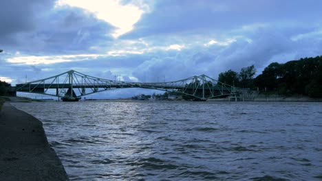 Beautiful-fast-moving-dark-gray-rain-clouds-over-the-Oskara-Kalpaka-swing-bridge-in-Liepaja-city-in-evening,-wide-shot