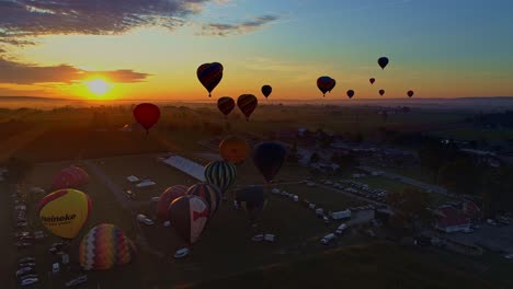 Luftaufnahme-Eines-Morgendlichen-Starts-Von-Heißluftballons-Bei-Einem-Ballonfestival-Vom-Befüllen-Bis-Zum-Abheben,-Wie-Von-Einer-Drohne-Gesehen