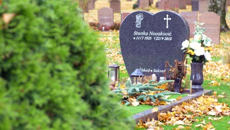 A-beautiful-grave-stone-on-an-autumn-day-in-Kviberg-cemetery-in-Gothenburg,-Sweden---panning-shot