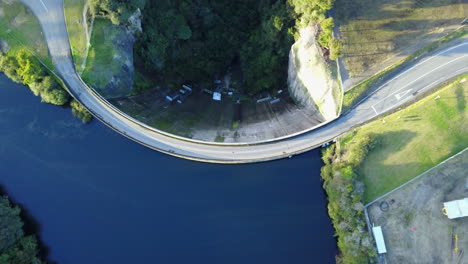 Aerial-top-view-drone-shot-of-Dam-with-blue-water,-Green-forest-and-white-birds-flying-by