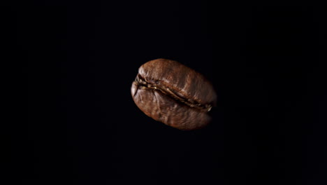 Nahaufnahme-Einer-Sich-Drehenden-Kaffeebohne-Mit-Schwarzem-Hintergrund-Und-Sanftem-Licht-Von-Links
