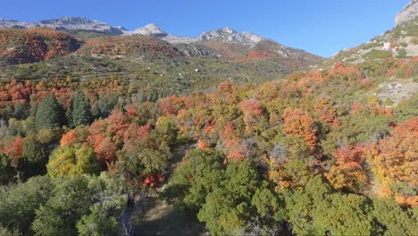 A-drone-flies-past-the-rocks-and-slopes-of-Dry-Creek-Trailhead-in-Alpine,-Utah-as-leaves-change-into-brilliant-fall-colors