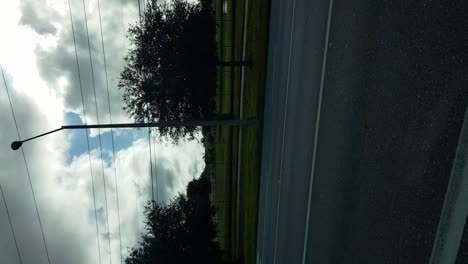 Vertical-view-of-driving-on-central-Florida-streets-with-thick-cumulus-clouds-in-blue-sky
