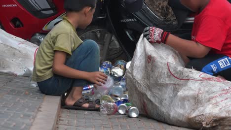 Niño-Camboyano-Sentado-Y-Clasificando-Latas-Y-Botellas-De-Plástico-De-Un-Solo-Uso-En-Un-Saco