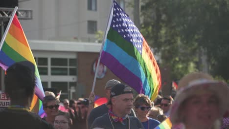 American-Gay-Pride-Flag-Waving-in-Air-With-People-Marching-in-Street-at-River-City-Pride-Parade-in-Jacksonville,-FL