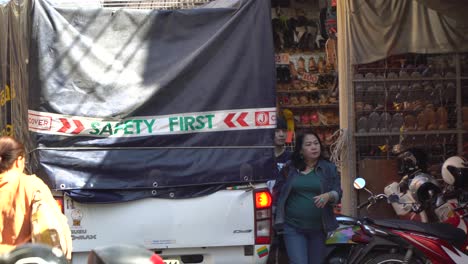 La-Gente-Camina-Por-La-Calle-Al-Lado-Del-Mercado-Local,-Los-Autos-Pasan,-Alguien-Está-Comiendo