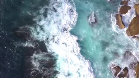 Top-down-bird-eye-view-of-strong-and-danger-ocean-waves-crashing-on-to-the-rocks