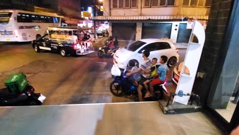 Family-gets-on-to-motorcycle-at-night-in-Pattaya,-Thailand-and-rides-away
