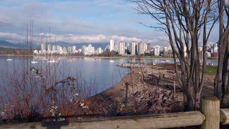 Sunny-December-day-in-Kitsilano-Beach,-Vancouver-overlooking-dog-beach-with-apartment-buildings-and-a-snowy-mountain-in-the-background