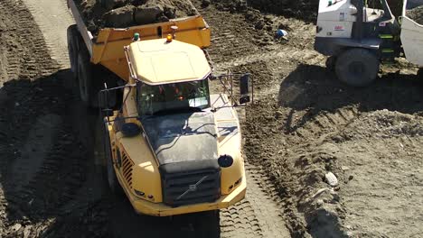Close-aerial-view-of-a-dumper-truck-moving-earth-reversing-on-a-large-construction-site-in-the-UK