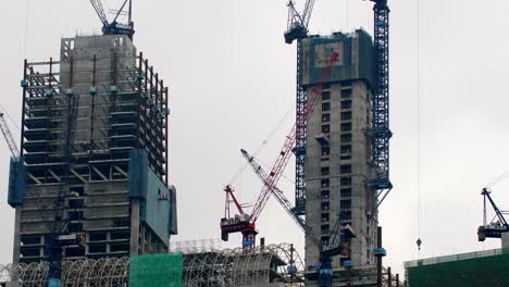 Office-and-residential-buildings-under-construction-with-cranes-and-support-beams-visible,-Locked-establishing-shot