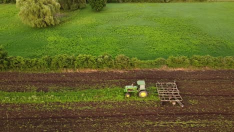 Farm-Tractor-Tilling-Crop-Field-In-Monroe-County,-Michigan---aerial